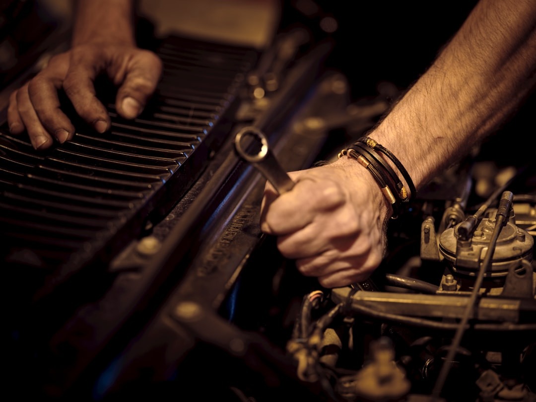 Hands repairing an engine with a wrench.