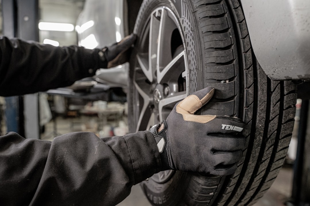 Mechanic inspecting a car tire on an alloy wheel.